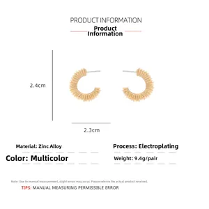 Détail de boucles d'oreilles dorées en C avec texture plissée et dimensions 2,4 cm x 2,3 cm