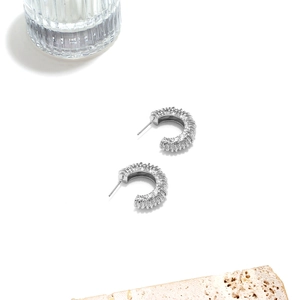 Gros plan sur des boucles d'oreilles argentées en C avec finition métallique striée vintage