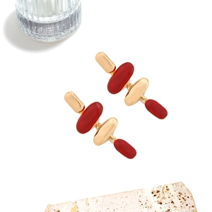 Boucles d'oreilles pendantes géométriques rétro en or et résine bordeaux sur marbre