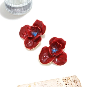 Vue détaillée des boucles d'oreilles fleurs en émail rouge 3D sur un socle en pierre