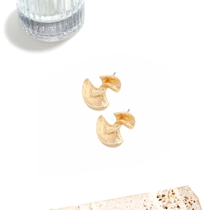 Macro detail of gold irregular geometric stud earrings with hammered metal texture