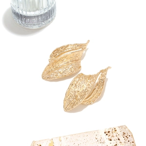 Detail of gold hollow geometric earrings showing irregular texture and brushed finish