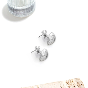 Detailed close-up of silver geometric earrings featuring a hammered texture on a stone plate