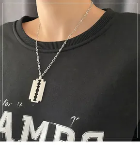 Primo piano di una collana con ciondolo a lama di rasoio in acciaio al titanio su un modello