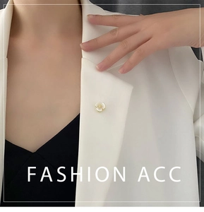 Close-up of shell flower brooch with gold edges pinned on a white blazer collar