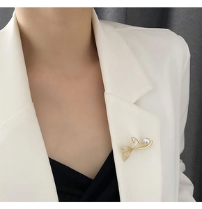 Detail of a gold bee brooch with pearls and zircons on a white blazer lapel