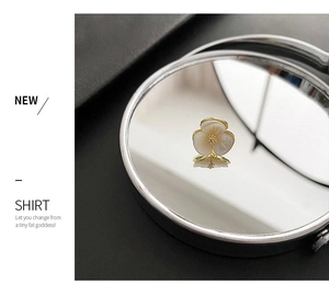 Detailed macro view of a gold flower brooch with shell petals and diamond center
