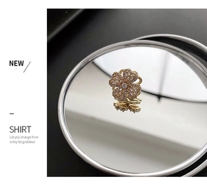 Macro shot of rotatable gold flower brooch with pavé diamonds on reflective mirror