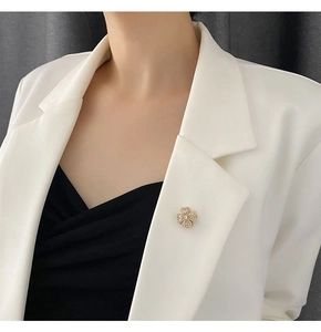 Rotating golden flower brooch with crystals pinned on a white blazer lapel