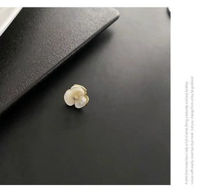 Macro shot of shell flower brooch with golden edges and petals on grey texture