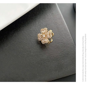 Close-up of golden four-leaf clover ear cuff inlaid with crystals and zircons
