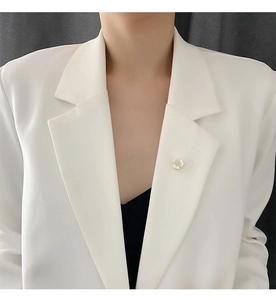 Detail of shell flower brooch with gold trim on a white suit collar for fixing neckline