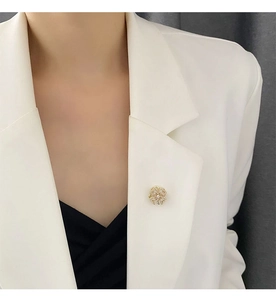Exquisite golden rotating flower brooch with sparkling pavé crystals on a white blazer