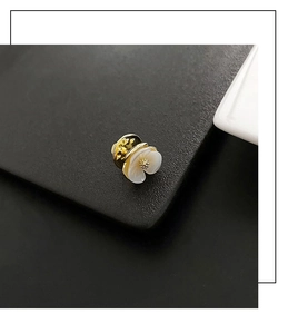 Macro shot of shell flower brooch with gold petals and secure pin back on black leather