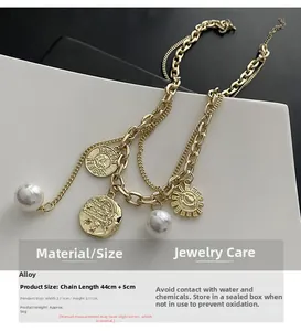 Detail of layered gold necklace with pearls, coin pendant, and sun face charm