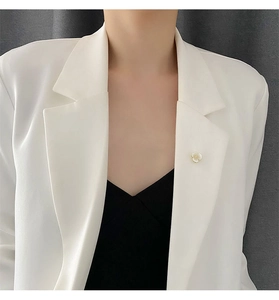 Detail of shell flower brooch pinned on collar for neckline styling on white suit