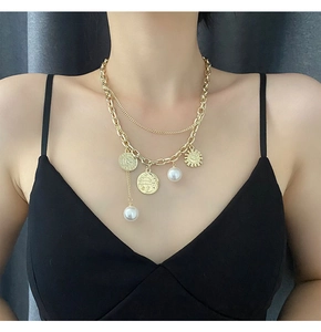 Close-up of layered gold necklace with retro coins, white pearls and sun pendant detail