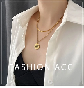 Detail of double-layer gold necklace with engraved coin pendant on white shirt