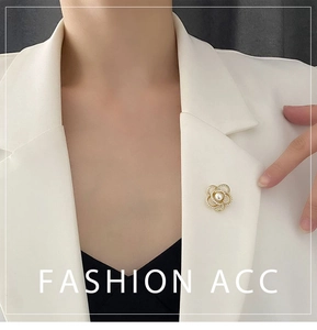 Détail d'une broche camélia avec perles sur le revers d'un blazer blanc