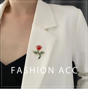 Detailed view of red rose enamel brooch with gold edges pinned on a white blazer
