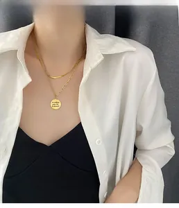 Close-up of double-layer gold necklace featuring a minimalist round letter pendant on a model