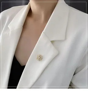 Détail d'une broche marguerite dorée avec zircon sur le revers d'un blazer blanc