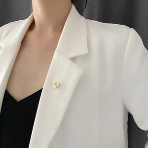 Elegant shell petal flower brooch with gold center pinned on a white blazer lapel