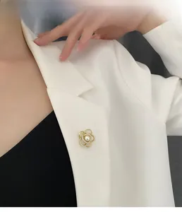 Gros plan d'une broche fleur dorée avec perle sur un revers blanc, vue détaillée