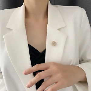 Elegant rotating golden flower brooch with sparkling diamonds on a white suit jacket
