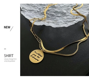 Close-up of gold double-layer necklace with snake chain and engraved round pendant