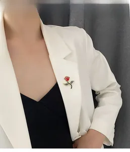 Detail shot of a red rose brooch with gold edges worn on a professional white blazer lapel