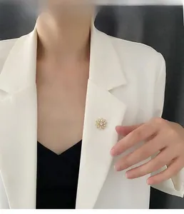 Détail d'une élégante broche fleur avec perles portée sur le revers d'un blazer blanc