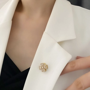 Elegant rotating clover brooch with white sparkling crystals on gold metal base