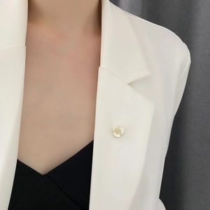 Exquisite shell flower brooch with pearl white petals and gold core on white suit jacket