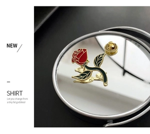 Detail of artistic red rose brooch with green leaves on a reflective mirror background