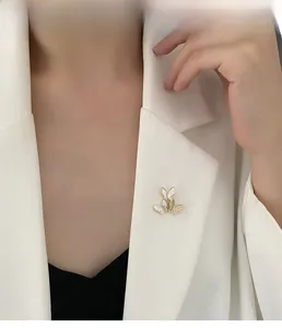 Close-up of three butterfly shell brooches with cubic zirconia on a white suit jacket
