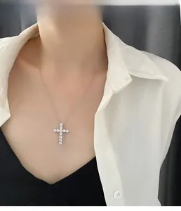 Detail of silver cross necklace with sparkling cubic zirconia worn by model