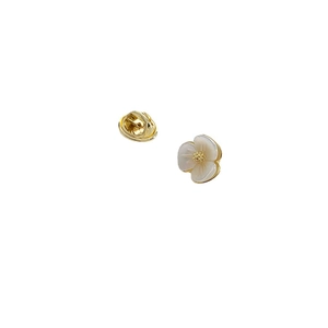 Elegant gold flower brooch with white shell petals and gold center on white background