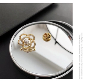 Détail d'une broche fleur dorée avec perles sur miroir pour costumes et pulls