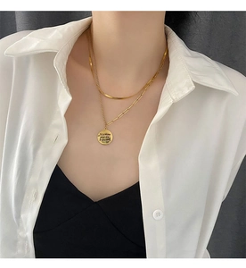 Detail of layered gold double chain necklace with round pendant on white shirt