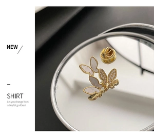 Detail of three butterfly brooches with shell wings and zircon inlay on a mirror