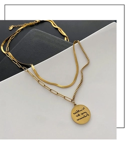 Detail of layered gold snake chain and paperclip link necklace with circular pendant