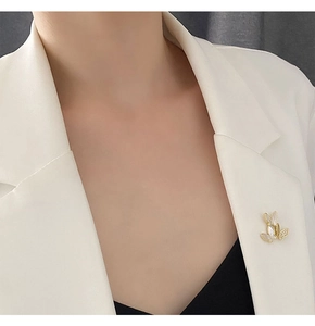 Close-up of golden butterfly brooch with shell inlay on a white blazer lapel