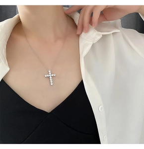 Detailed view of silver cross necklace with sparkling zircon pendant worn by female model