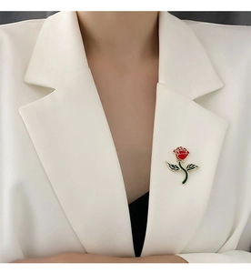 Detail of a red rose brooch with gold edges pinned on a white suit lapel
