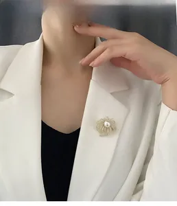 Detailed view of an elegant sunburst pearl brooch with rhinestones on a white blazer