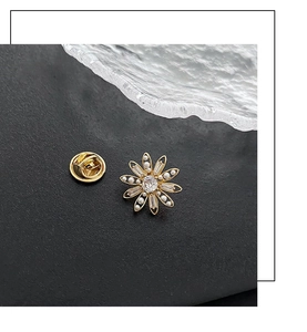 Détail macro d'une broche marguerite dorée ornée de zircons et de perles blanches