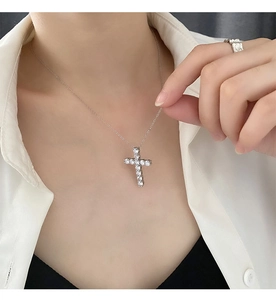 Detail view of silver cross pendant with white zirconias on model with white shirt