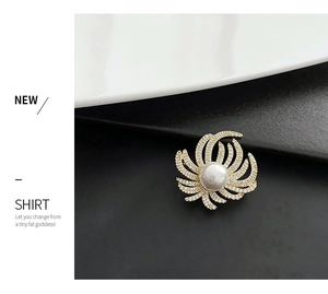 Detailed close-up of a luxury gold brooch with a large white pearl and micro-paved zircons