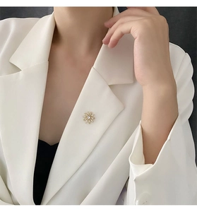 Vue détaillée d'une broche fleur dorée avec cristal centrée sur le revers d'un blazer